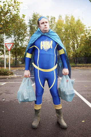 Overweight Man Dressed as Hero Holding Shopping Bags